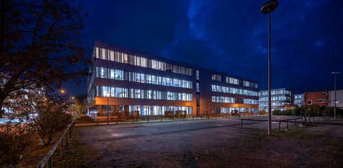 Siemens office buildings illuminated in the evening, empty parking spaces in front, Erlangen,