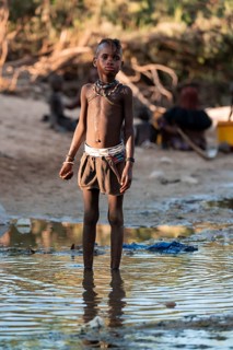 Himba child washing with water on a river, traditional Himba, Kaokoveld, Kunene, Namibia