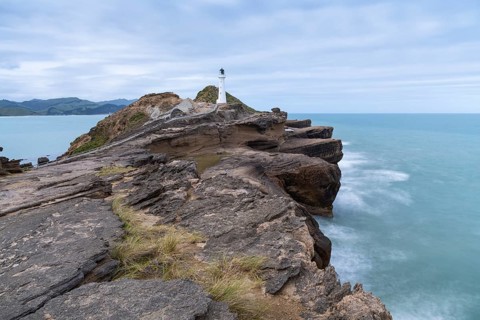 Castlepoint lighthouse on a rock, sea, long exposure. Castlepoint, Wairarapa Coast, Wellington
