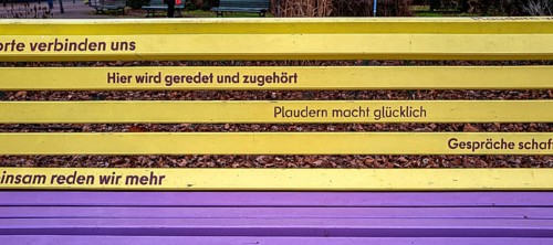 Park bench with slogan for talking and chatting in yellow and purple, Berlin, Germany
