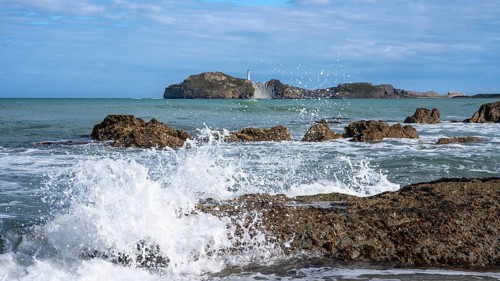 Castlepoint Beach and Castlepoint Lighthouse, ocean, waves, surf, sandy beach, rocks. Castlepoint,