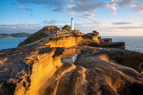 Castlepoint lighthouse on a rock, sea, sunrise. Castlepoint, Wairarapa Coast, Wellington Region,