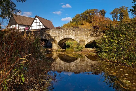 The river Hönne with the old Hönnetalbrücke in autumn with half-timbered house in Volkringhausen,