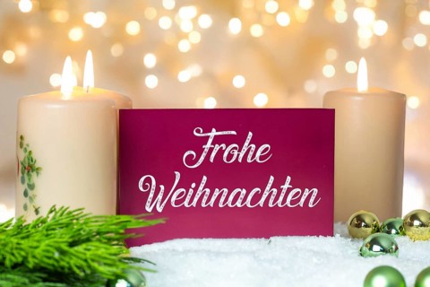 Greeting card with the inscription FROHE WEIHNAHCHTEN between Christmas accessories with bokeh in