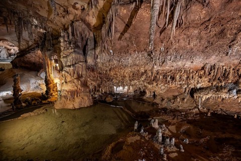 Stalactites and stalagmites, rock formations in a stalactite cave with water basin, Grotta del