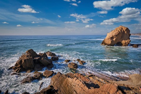 Penedo do Guincho, a large boulder rock arch at Praia da Santa Cruz, Portugal, with ocean waves and