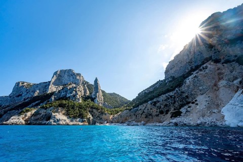 Light blue clear sea on a dream beach on Cala Goloritzé, picturesque rocky coast with sun stars,
