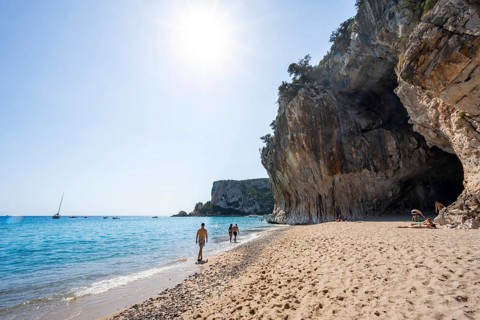 Sandy beach beach and steep cliffs with caves at Cala Luna, Golfo di Orosei, Baunei, Sardinia,