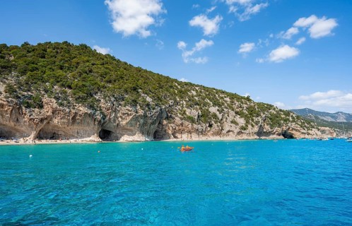 Kayakers in clear blue water, picturesque rocky coast, cliffs and Cala Luna beach, Golfo di Orosei,