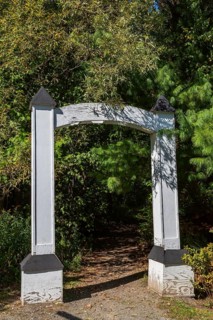 White painted wooden portal gate at start of hiking trail in public nature park in late summer,
