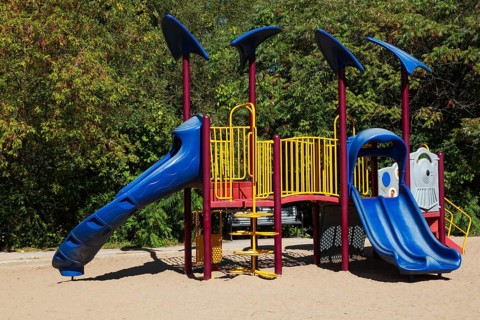 Kids playground equipment with slides, climbers and monkey bars installed in sandy ground in city