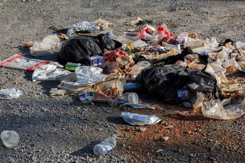 Recyclable plastic, paper and cardboard items discarded on the ground in public park, Quebec,
