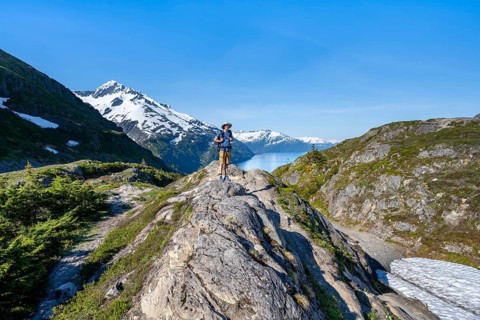 Hikers on Portage Pass, snow-covered mountains and Fjord Passage Canal, near Whittier, Alaska, USA