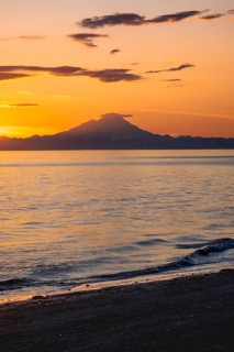 View of Cook Inlet on white mountain peaks of Mount Redoubt at sunset, picturesque golden light of