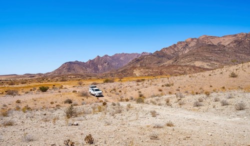 Toyota Hilux off-road vehicle on a sandy track, desert landscape with Brandberg, Erongo,