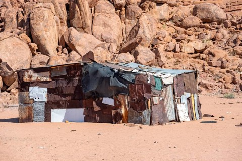 Simple poor huts made of corrugated iron and wood, desert landscape, barren landscape with hills of