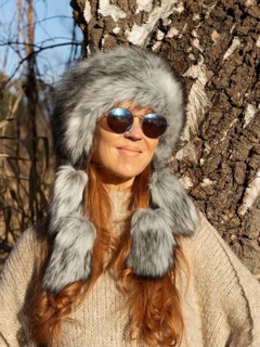 Slender pretty woman with Mongol hat, red hair and warm winter colors between birch forest and