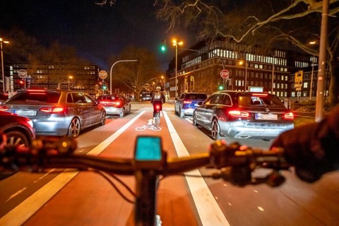 Cycling in the city, in the dark, in the evening, cycling on a bike lane, marked in red,
