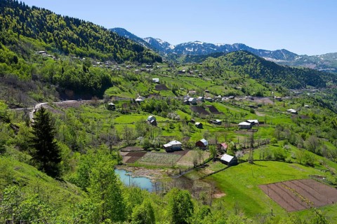 Green hilly landscape with scattered farms and small villages under blue skies, village in the