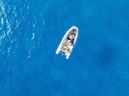 Young woman and young man lying in a motor boat on a blue sea, top-down, aerial view, Golfo di