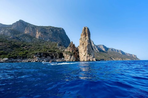 Picturesque rocky coast, cliffs with Pedra Longa pinnacle in the evening light, blue sea, Golfo di