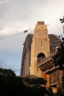 Side view of Sydney Harbour Bridge at sunset with the Australian flag
