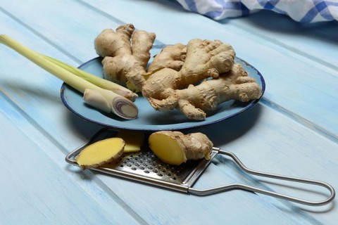 Ginger tubers and lemongrass on plate, grater with ginger pieces