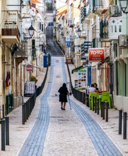 Sticker-covered sign with bicycles and surfboards, Nazaré, Portugal