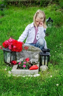 Grieving blonde 7-year-old girl at her cat's grave at pet cemetery in Ystad, Skåne County, Sweden,