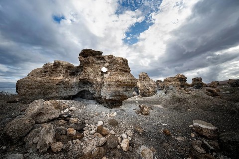 Eroded rock formations in volcanic landscape with dramatic cloudy skies, Ciudad Estratificada or