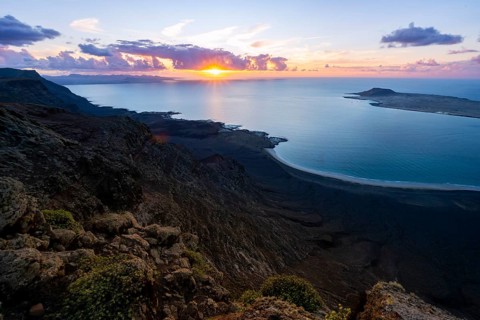 View from steep cliffs to sea and coast with sun stars, Mirador del Porrito viewpoint at sunset,