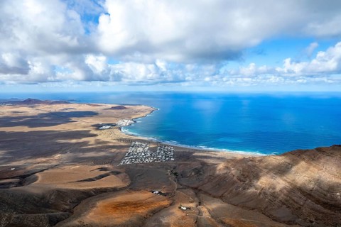 View from the Risco de Famara cliffs to the coast and the sea with the Famara beach, Playa de
