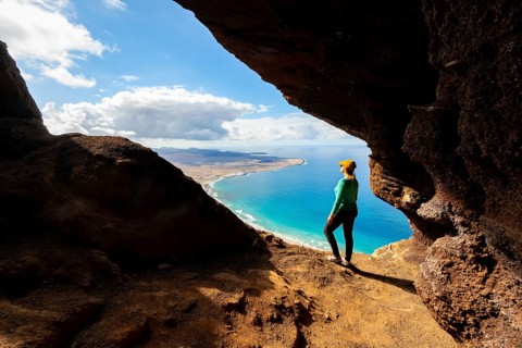 Tourist in the Cueva de las Cabras cave, young woman enjoying the view from the Risco de Famara