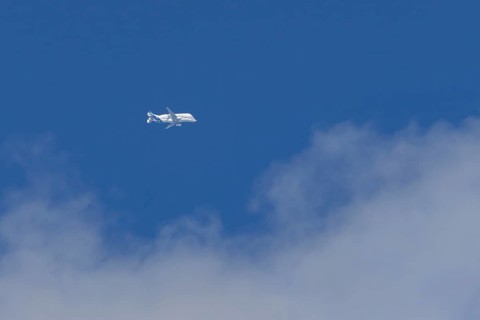 Airbus A330-743L Beluga XL cargo jet aircraft flying in a blue sky with white clouds, England,