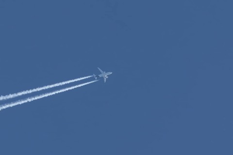 Airbus jet passenger aircraft flying in a blue sky with contrails or vapour trails behind, England,