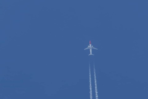 Boeing 737 jet passenger aircraft of Norwegian Air airlines flying in a blue sky with contrails or