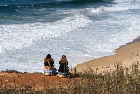 Tourists watch the waves of the Atlantic on the rocky plateau of Sito, also known as Forte São