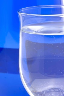 Glass with mineral water, small carbonated pearls on the edge of the glass, drinking water