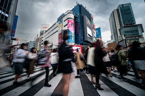 Crowd crossing zebra crossing on a large intersection, motion blur, back modern houses with