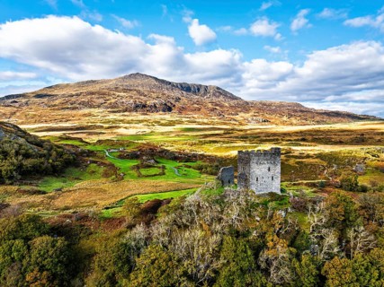 Autumn colours over Castell Dolwyddelan and Eryri Mountains from a drone, Snowdonia, Conwy County
