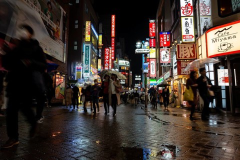 Busy pedestrian zone with many shopping centers and stores, illuminated with lots of neon signs at