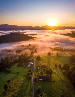 Sunrise over a fog covered village in a rural landscape, golden morning light, serene autumn