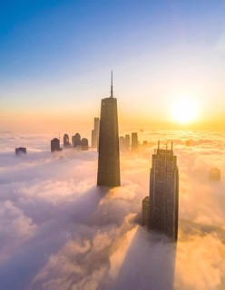 City scape emerging from a dense enveloping fog in sunrise and skyscrapers piercing the haze, big
