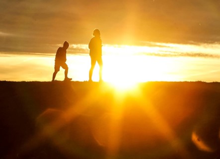 Woman and child walk across a dike on the island of Fehmarn at sunset, 13.10.2025, Fehmarn,