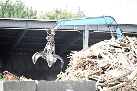 Loading crane with grab arm for loading wood waste for wood pellet production on the premises of