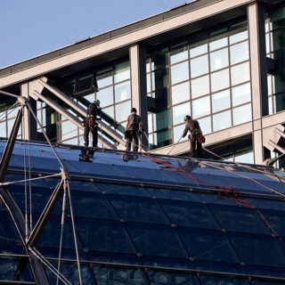 Three male glass cleaners abseiling down a glass roof of Berlin Central Station to clean windows,