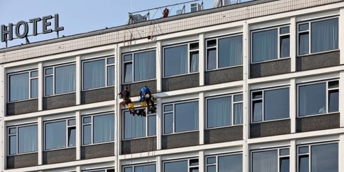 Two male glass cleaners abseiling down the hotel façade to clean windows, aletto Hotel Kudamm,