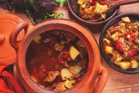Chanakhi, a Georgian dish. in a clay pot, on a wooden table, stewed meat with vegetables, homemade,
