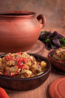 Chanakhi, a Georgian dish. in a clay pot, on a wooden table, stewed meat with vegetables, homemade,
