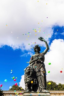 Colourful balloons rise high above the statue of Bavaria into the white-blue sky, grand finale of